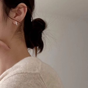 Minimalist S925 sterling silver knotted hoop earrings worn by a model in soft lighting