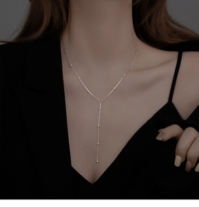 Detailed view of silver Y-shaped tassel necklace with bead accents on a female model