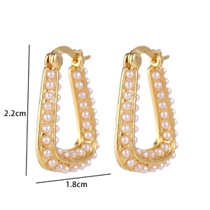 Macro view of triangular geometric earrings with gold plating and white pearls