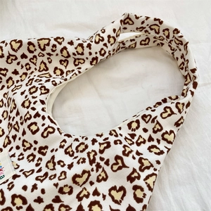 Detailed close-up of heart-shaped leopard print pattern on high-quality canvas tote bag