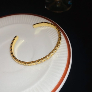 Gros plan détaillé du bracelet jonc doré orné de diamants sur plateau céramique