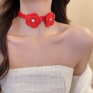 Close-up of red handcrafted knit rose choker with white pearl accents on the flowers