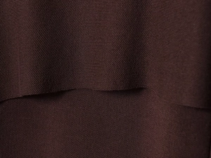 Gros plan du tissu en maille marron chocolat avec coutures superposées et texture fine