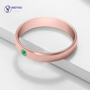 Macro shot of rose gold stainless steel ring with a round inlaid green gemstone