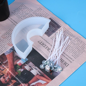 Rainbow shaped silicone mold with cotton candle wicks on a magazine background
