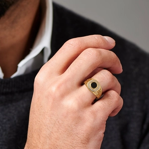 Men's gold ring with black center stone and white zircon accents worn on hand