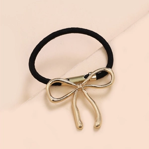 Detail of black elastic hair tie featuring a polished gold metal bow charm ornament