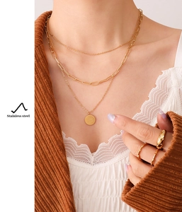 Detailed close-up of layered golden stainless steel necklaces with a Carpe Diem pendant