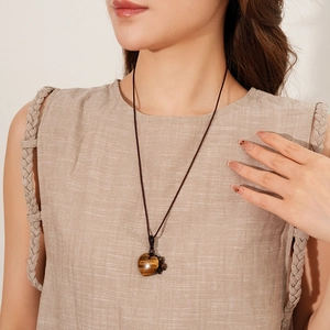 Tiger eye heart pendant necklace featuring hand-woven brown rope on a linen-clad model
