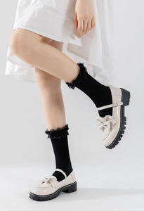 Détail de chaussettes blanches à volants avec chaussures Mary Jane en cuir verni et nœud