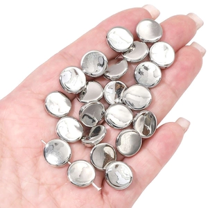 Close-up of shiny silver metallic round beads for DIY jewelry making held in palm