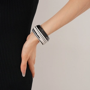 Detail shot of a minimalist black and white striped acetate open cuff bracelet on a model