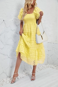 Detail view of yellow smocked midi dress with puffed sleeves and tiered skirt fabric