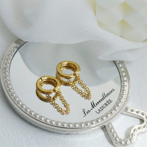 Close-up of golden tassel hoop earrings on a vintage mirror with floral background