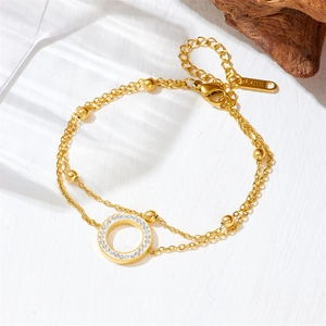 Double-layered gold titanium steel bracelet with a crystal circle pendant on white texture