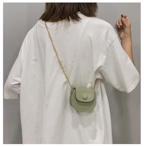 Détail du dos d'un mini sac selle vert avec bandoulière chaîne dorée porté par un mannequin