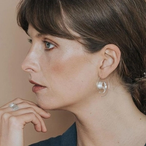 Boucles d'oreilles spirales en argent et bague large martelée portées par un mannequin