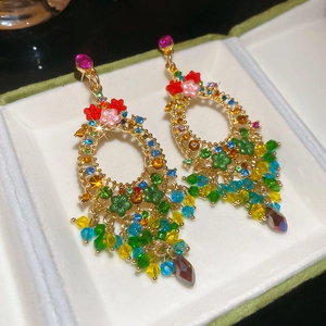Macro detail of sparkly floral earrings featuring colorful crystals and long bead tassels