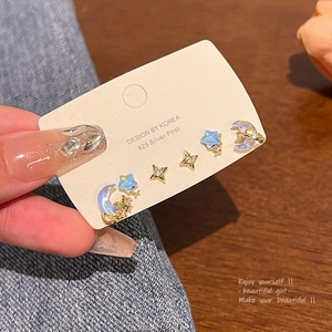 Detalle de pendientes de plata 925 con motivos de luna, estrellas y piedras azules