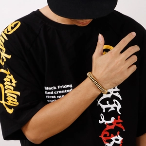 Close-up of a men's golden spiral spring bracelet on wrist with a casual black tee background