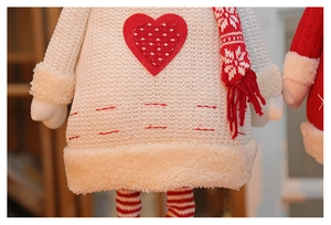Detail of knitted Christmas doll featuring red heart applique and soft plush trim