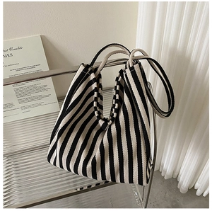 Detail of classic black and white striped canvas tote bag on a modern acrylic shelf