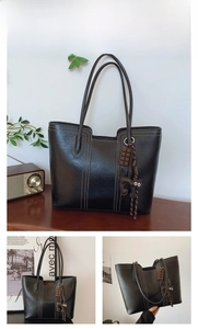 Detail view of black tote bag with white stitching and cute cat charm pendant