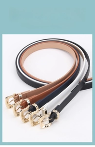 Close-up of four women's skinny belts in black, white, navy, and brown with gold buckles