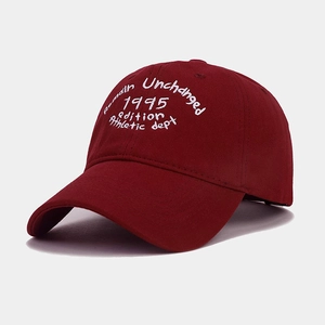Dettaglio del cappellino bordeaux con ricamo bianco e trama in twill di cotone