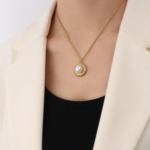 Close-up of vintage pearl pendant necklace with gold twisted rope frame on elegant model