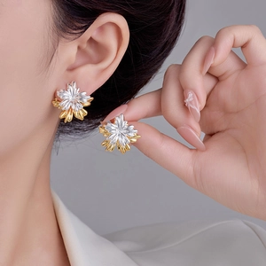 Elegant gold and silver two-tone layered flower stud earrings worn by a model