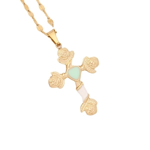 Golden cross necklace featuring rose engravings and a green heart gem on white cross pendant