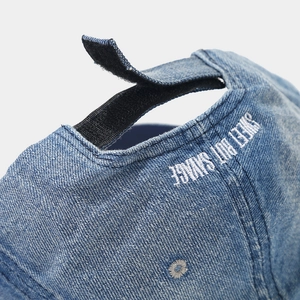 Close-up of denim baseball cap texture with adjustable strap and white embroidery