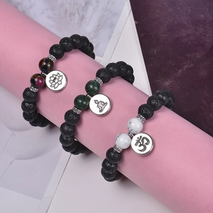 10mm black lava stone yoga bracelet with lotus and OM charms on a pink jewelry display