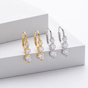 Détail de créoles en argent 925 avec trois pierres de zircone verticales en finition dorée