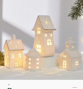 Close-up of warm white ceramic house ornaments with gold trim and glowing interior light