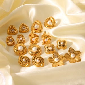Macro shot of gold-plated floral and geometric earrings with pearls on silk