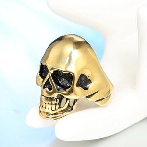 Detail view of a vintage gold punk skull ring with distressed finish on a hand model