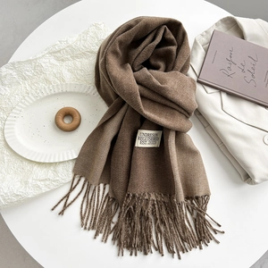 Detail of brown cashmere-like scarf with hand-tied tassels and white woven brand label
