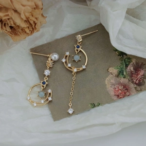 Detail of 925 silver needle earrings with asymmetric stars, moon and tassel charms