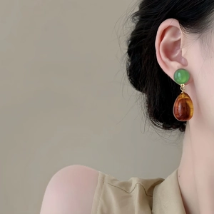 Detail of amber waterdrop resin earrings with green beads and gold metal connectors