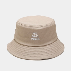 Detail of beige cotton bucket hat featuring white NO BAO VIBES embroidery and reinforced stitching
