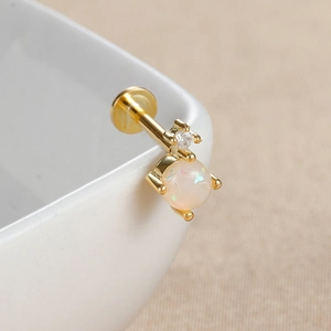 Gros plan d'un piercing labret doré avec opale ronde et zircon blanc sur céramique