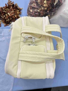 Detail view of large lightweight yellow toiletry bag with white zipper and handle