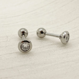 Macro view of titanium steel dumbbell stud earring with white cubic zirconia inlay
