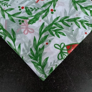 Detail of Christmas tissue paper featuring holly berries and bells on black background