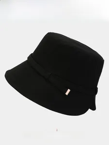 Detail of black cotton bucket hat featuring a decorative ribbon and golden metal buckle