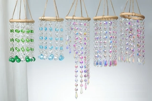 Detail of diverse wooden ring crystal suncatchers with emerald and azure teardrop beads