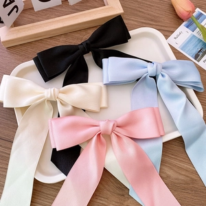 Elegant satin ballet-style double-layered bow hair clips in four pastel colors on a tray
