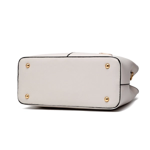 Detail view of the handbag base with gold anti-wear studs and fine leather texture